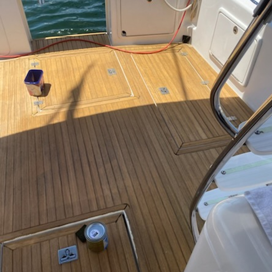 Wooden deck of a boat with a view of the water. A can of Semco Sealer Natural sits in the foreground.